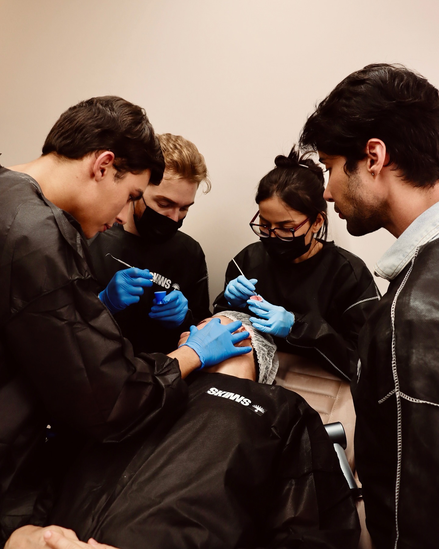 Grupo de alunos aplicando peeling juntos em paciente real